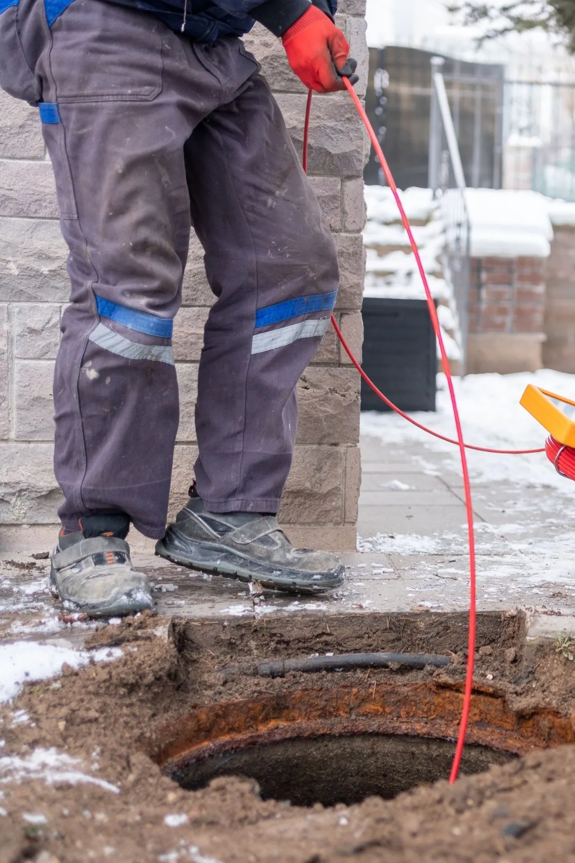 Technicien en plomberie effectuant un débouchage de drain à l’intérieur d’une maison à Saint-Jérôme